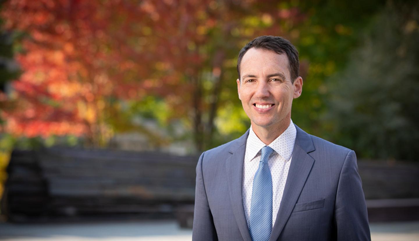 a man in a suit stands outside and smiles