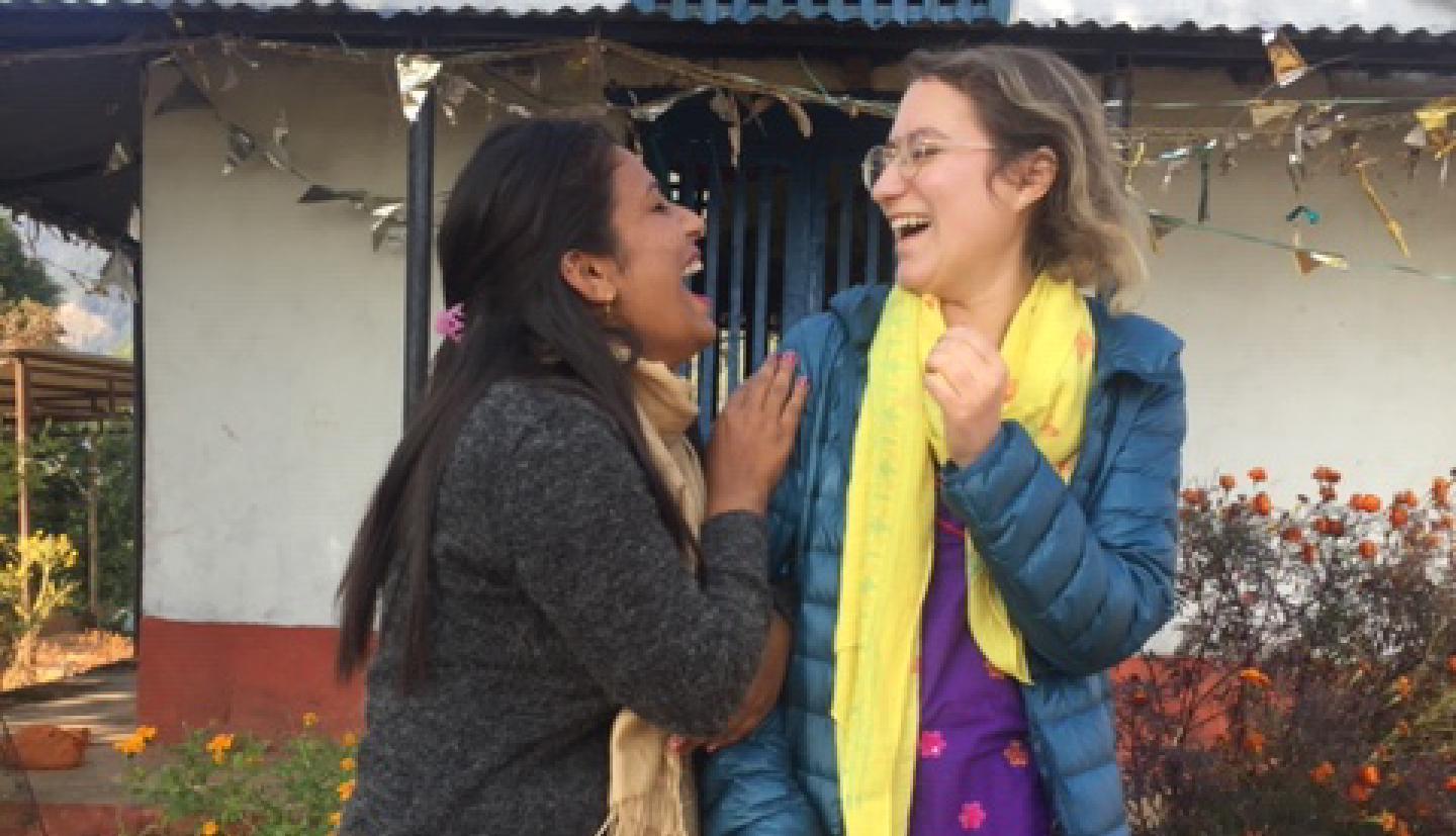 Two women stand and laugh together