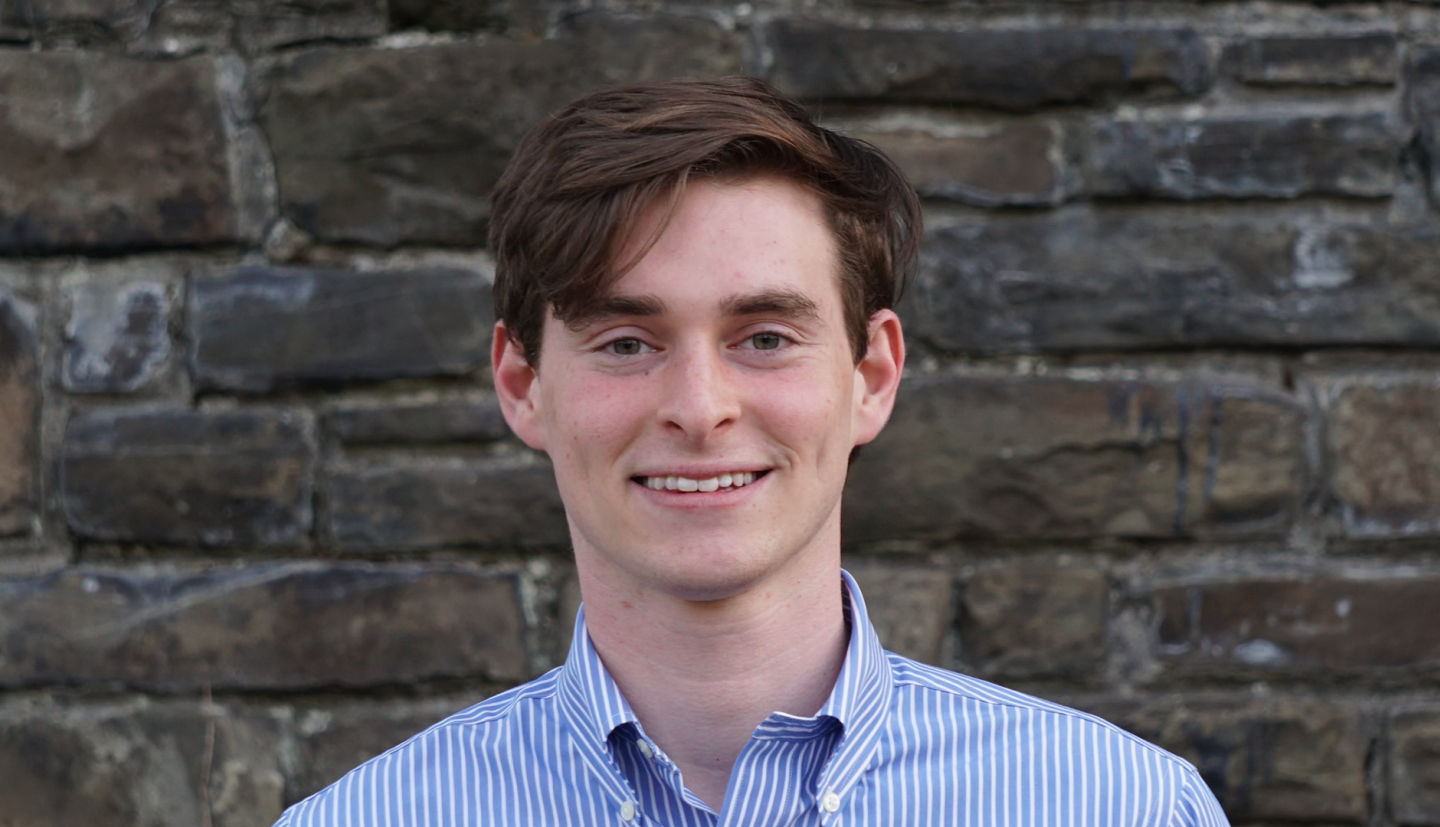 a student stands in front of a gray stone wall