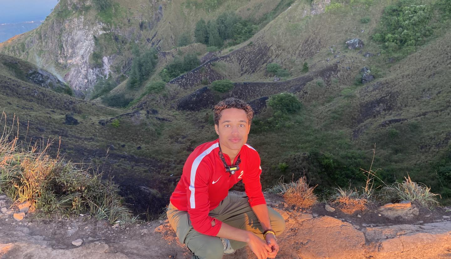 Person crouching in front of mountain