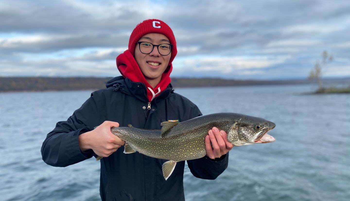 Person holding a fish in front of water
