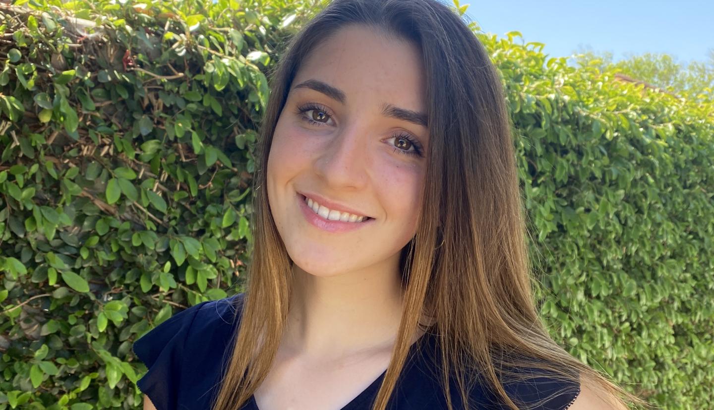 Girl smiling in front of bush