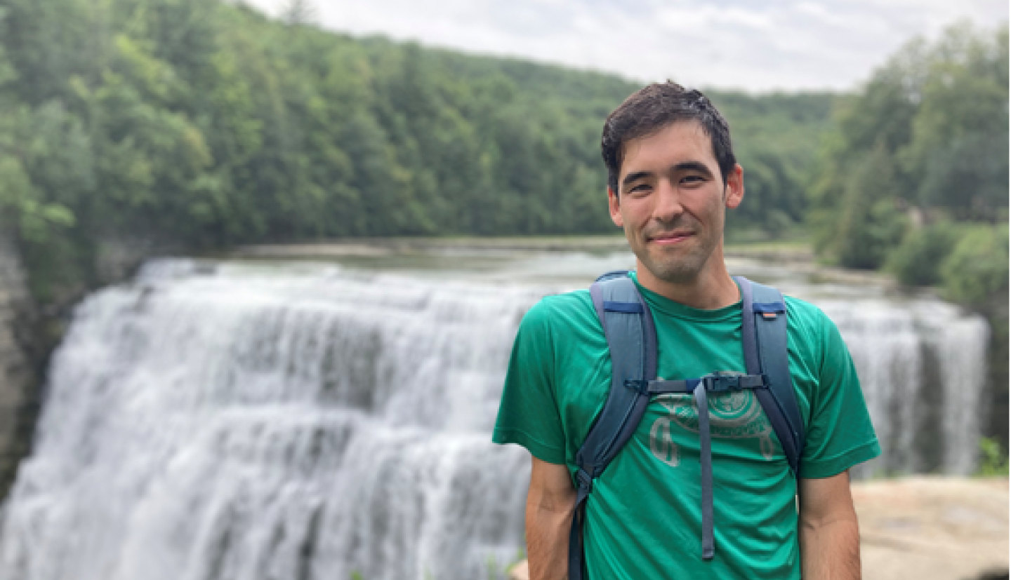 Kenji Doering stands in front of a waterfall.