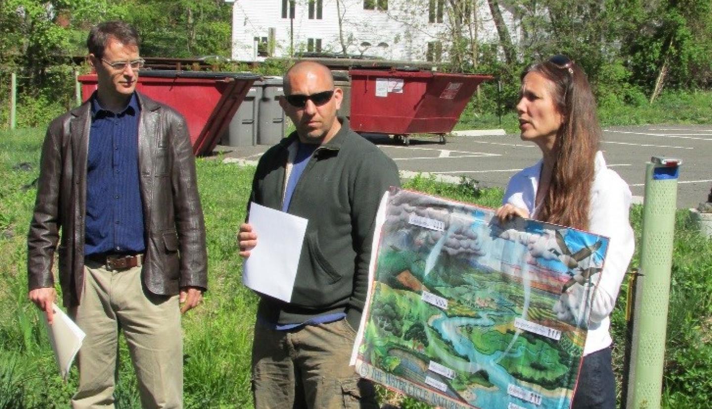 Three people present a poster along a tributary.