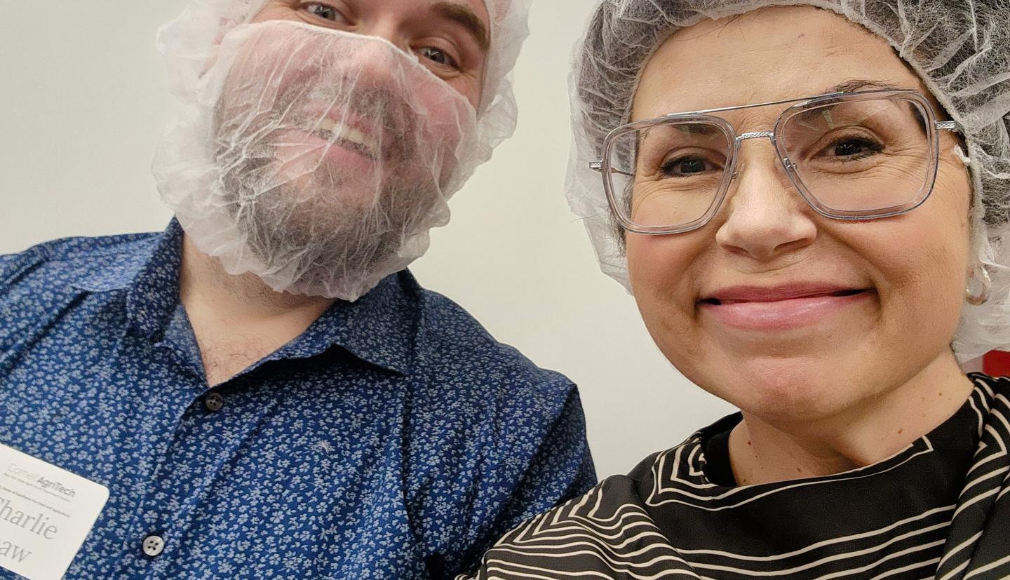 A man and woman wearing hairnets smiling for a selfie. 
