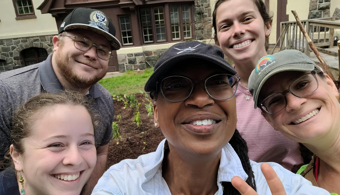 Individuals smile in front of garden