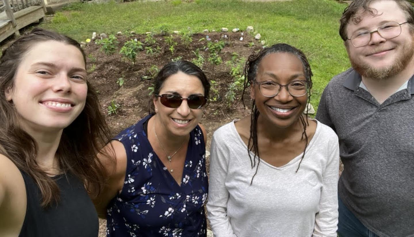 individuals smile in front of pollinator gardens