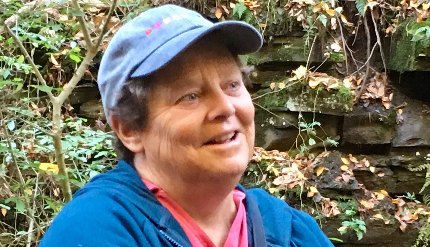 Barb Neal wearing a hat, smiling and looking off to the left