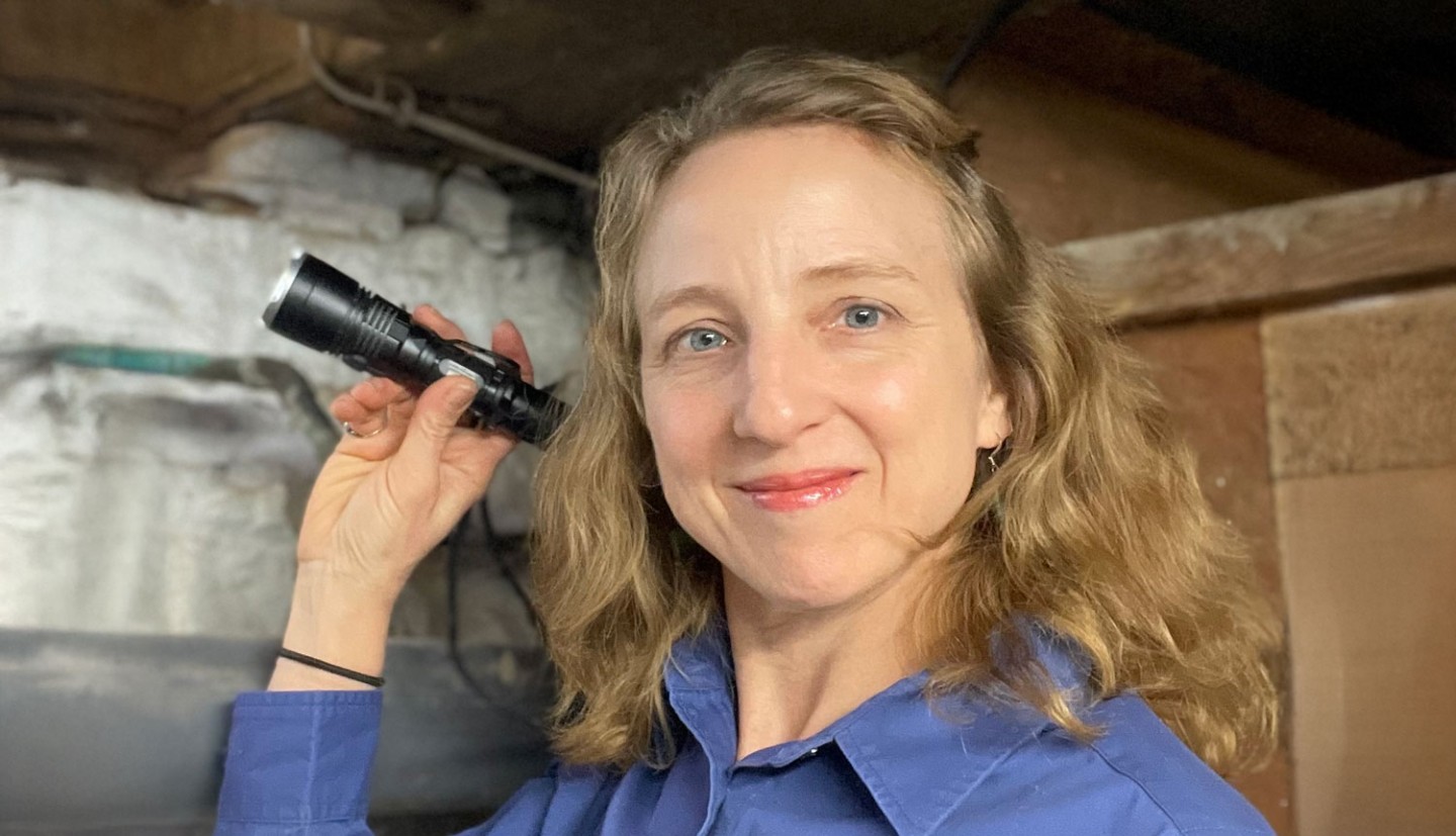 Susannah Krysko holding a flashlight and smiling, wearing a stop pests shirt