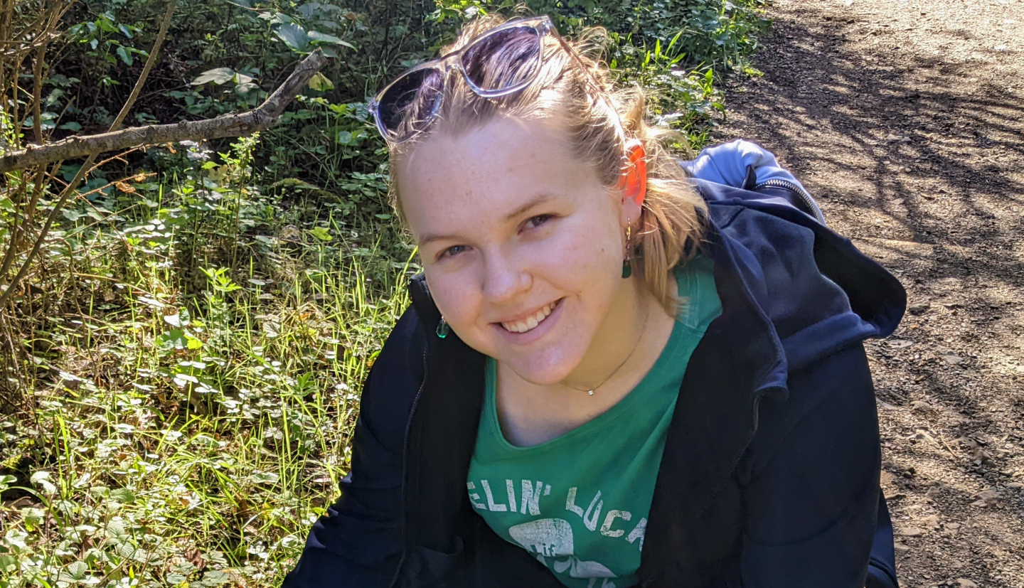 Girl smiling crouching down to touch the grass