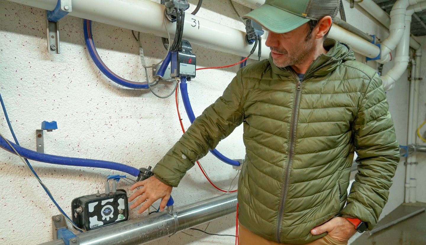 a man points at a piece of tech in a barn