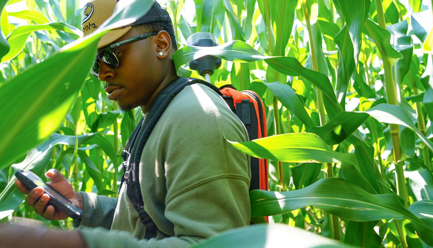 a man stands in a corn field holding technology