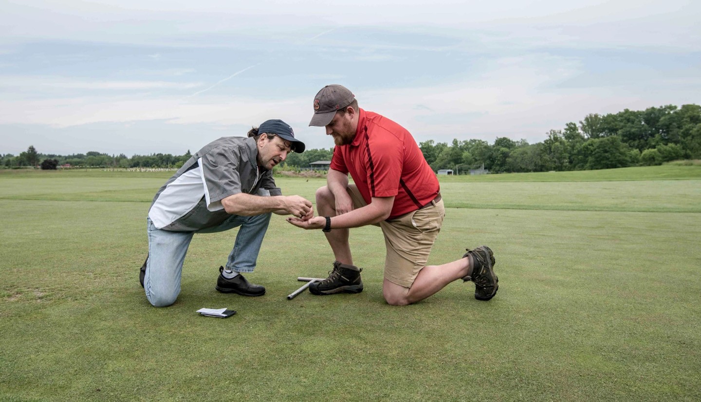 two men with soil sample on golf green