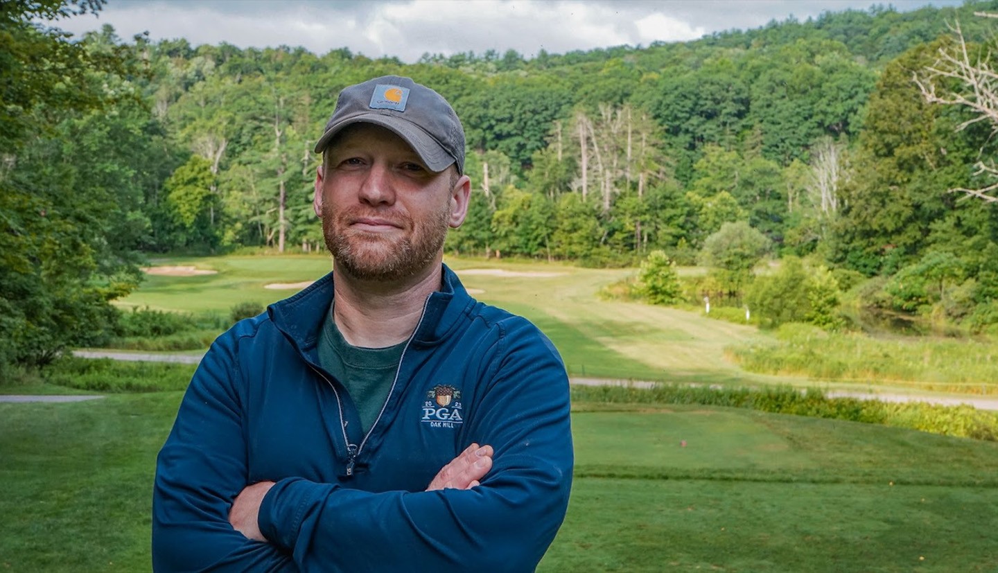 man with baseball cap and crossed arms on fairway