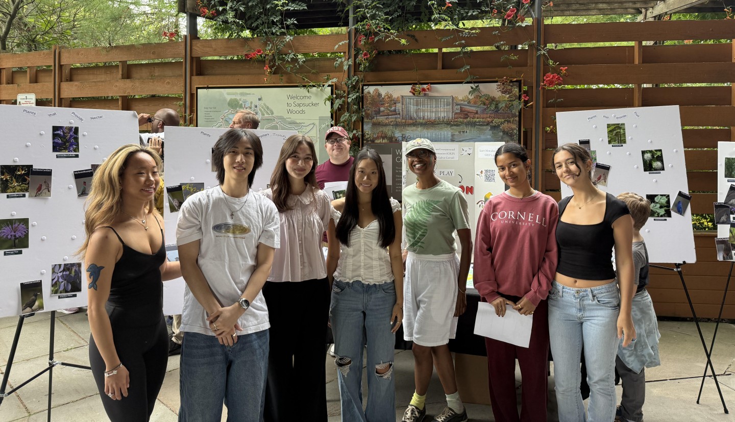 group of students stand in front of poster boards, smiling