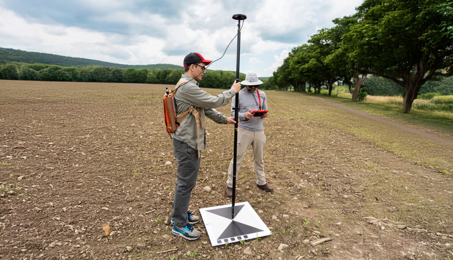 two men use gps in a farm field