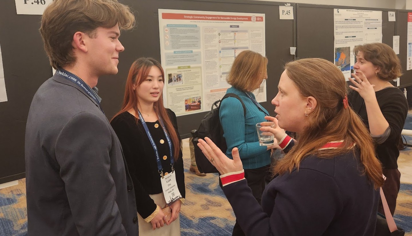 three individuals stand in front of a poster board