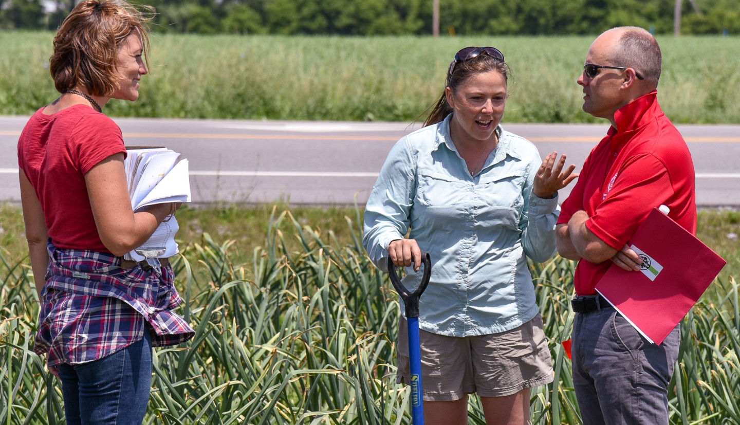 Crystal, Jud, and one other person discussing garlic at field day