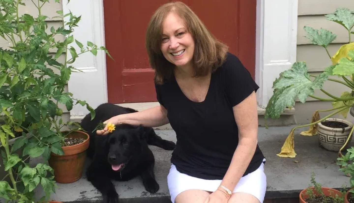 dawn Schrader sitting in front of a door petting a dog
