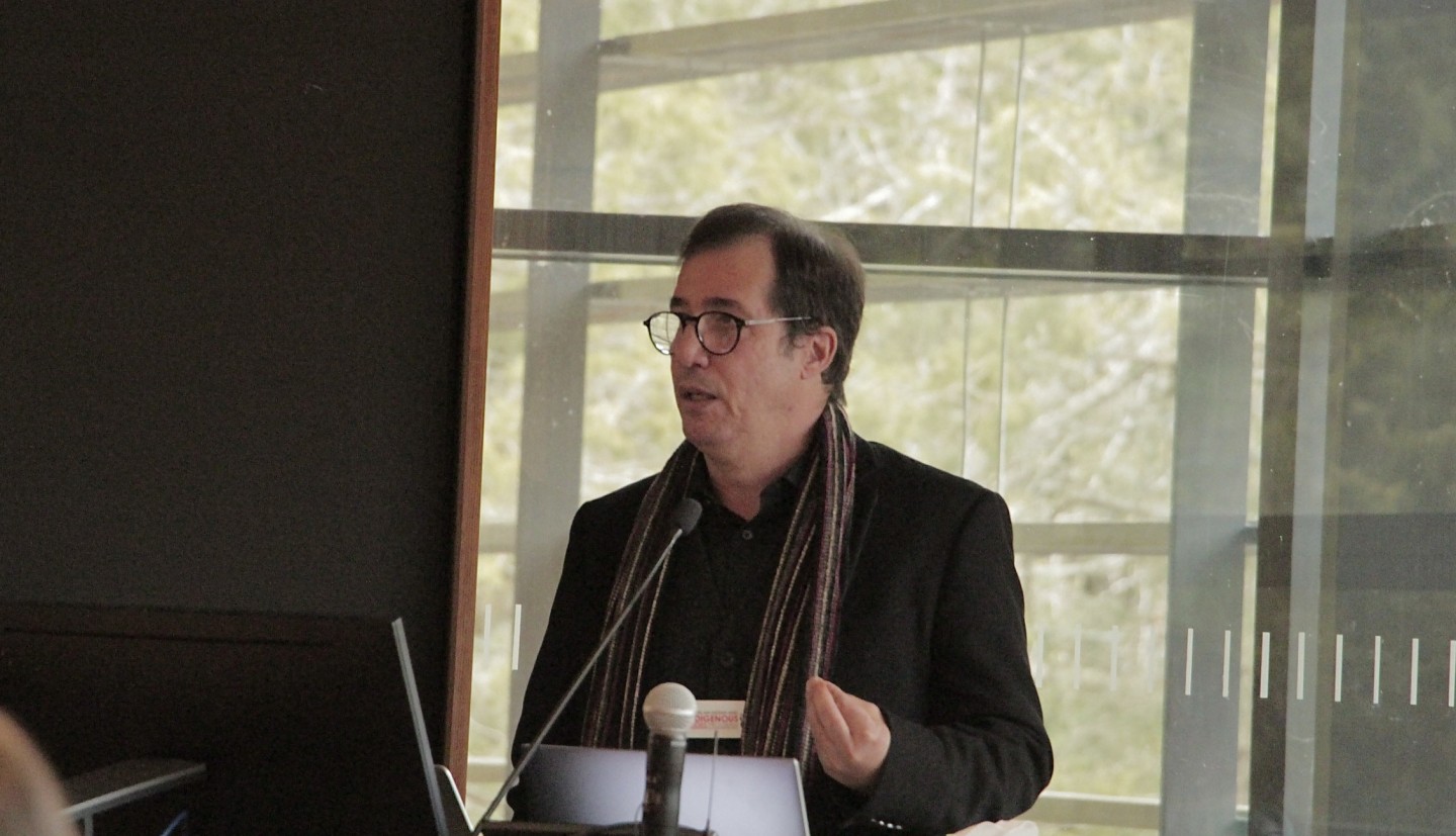 Troy speaks at a podium.