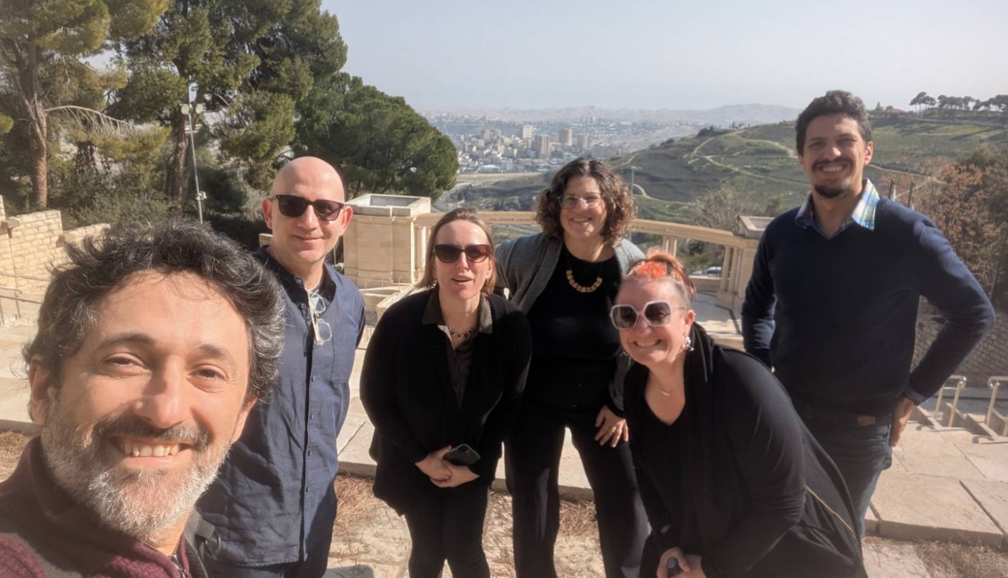 5 individuals stand and smile for a selfie