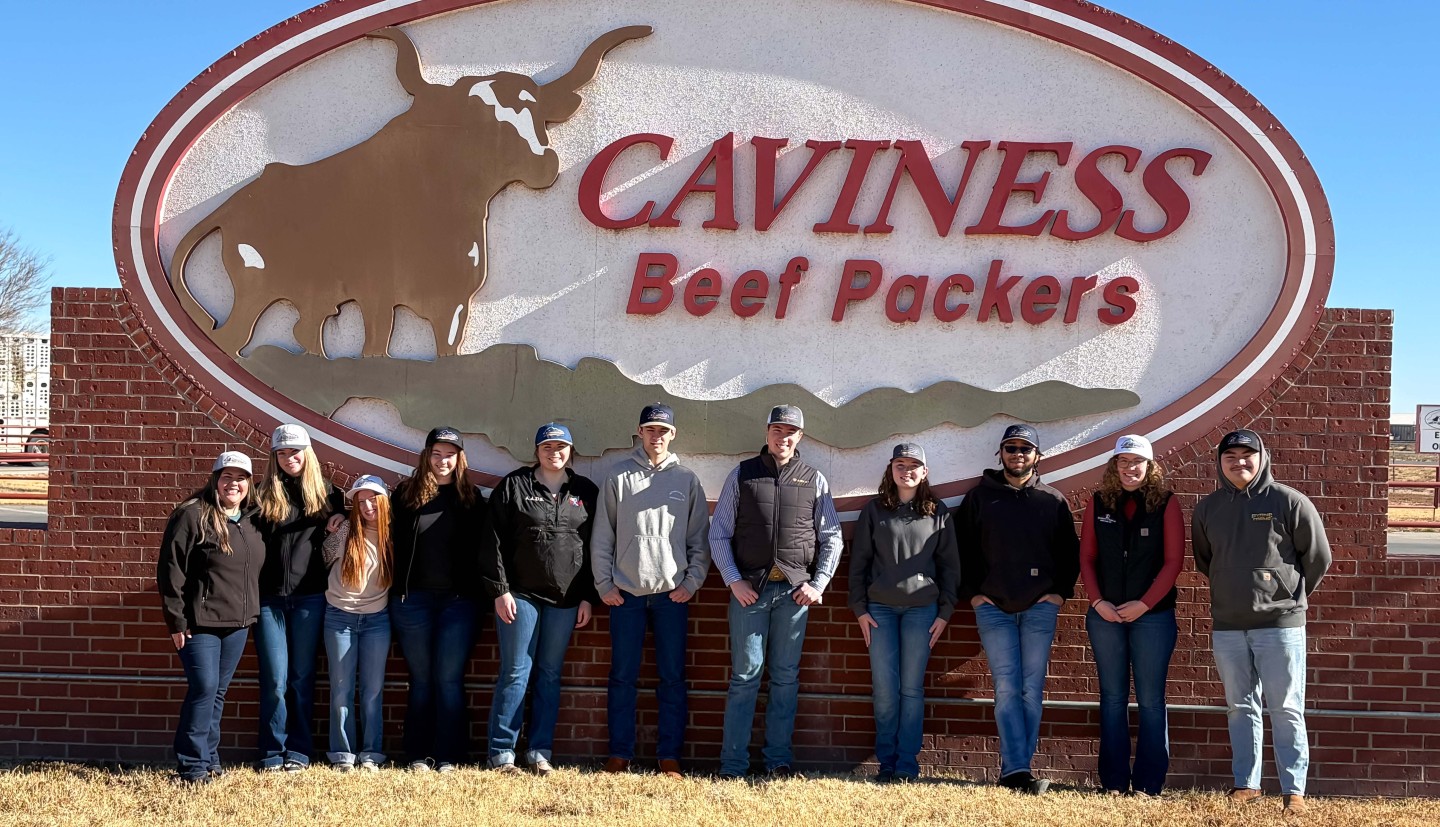 a group of people stand in front of a sign that says Caviness Beef Packers