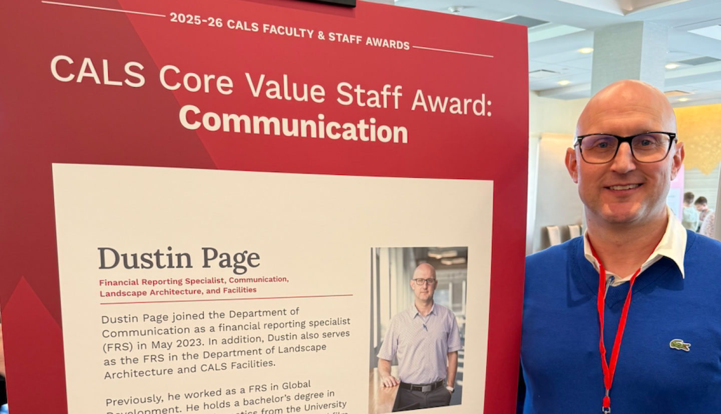Dustin Page stands in front of CALS Core Value Staff Award poster