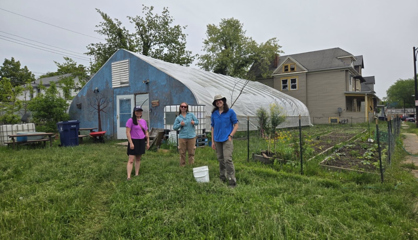 Mallory standing in front of a greehouse at Brewster Farm.