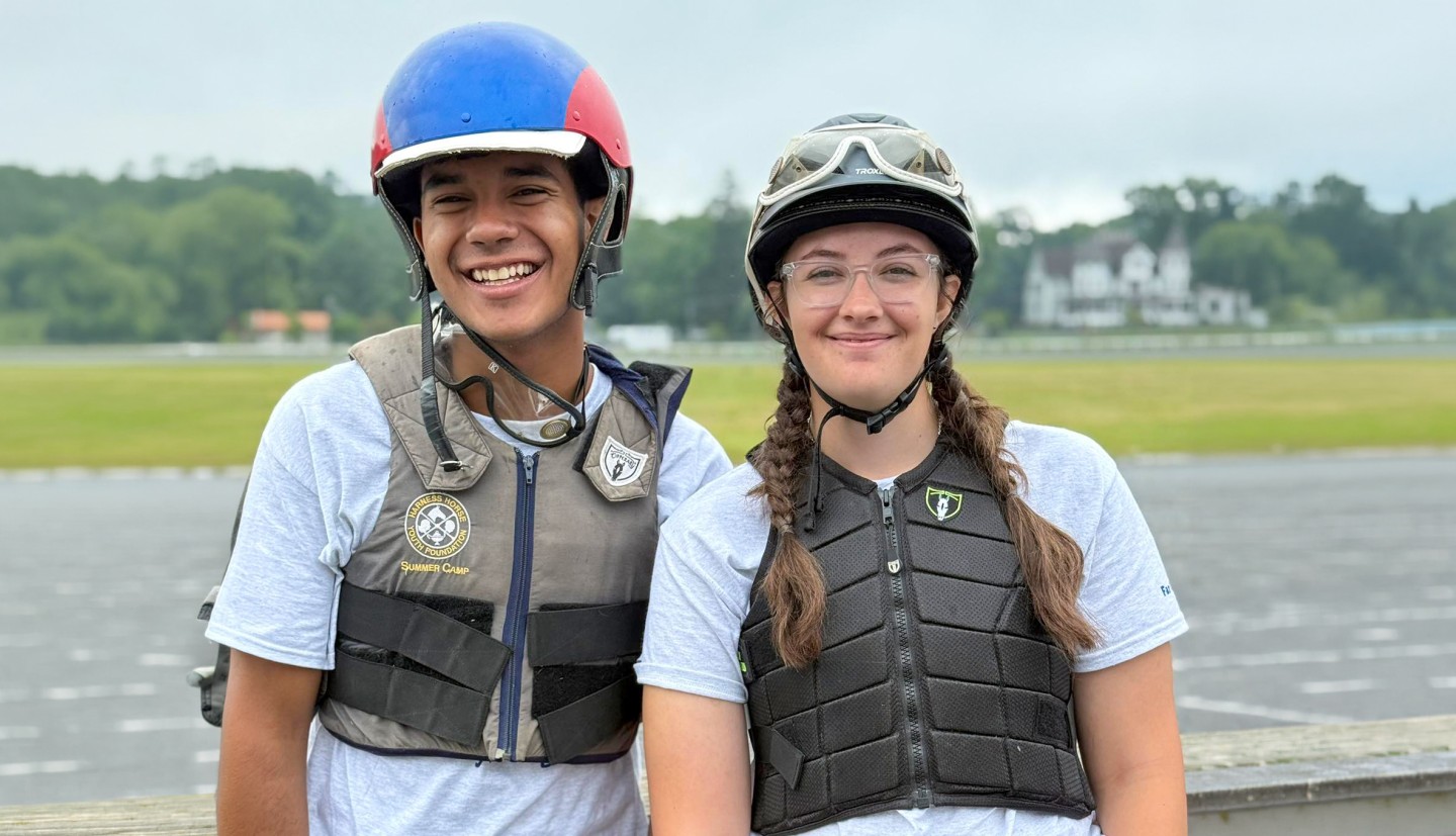 a young man and young woman dressed in horse protective gear stand together