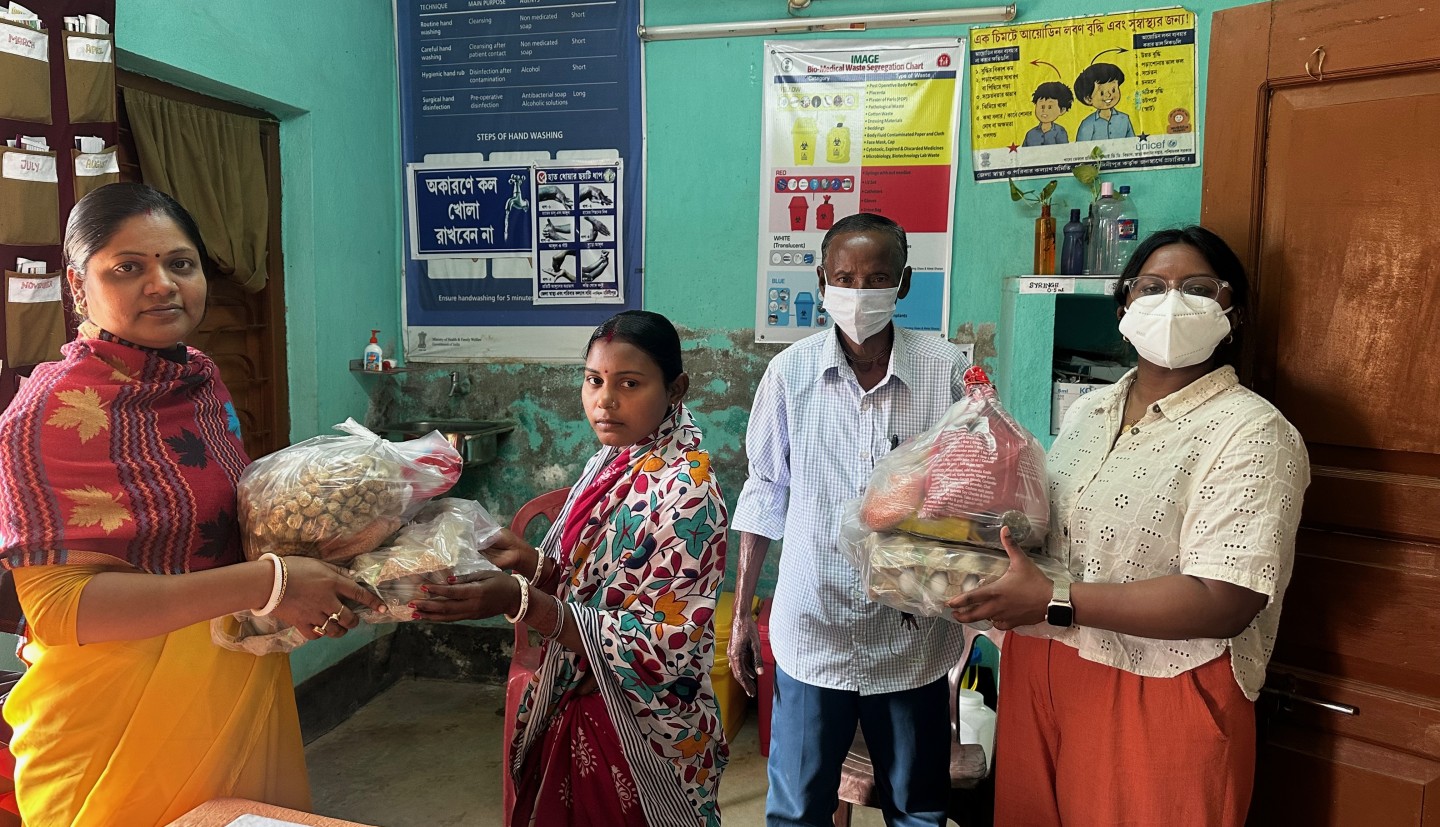 4 individuals stand holding groceries