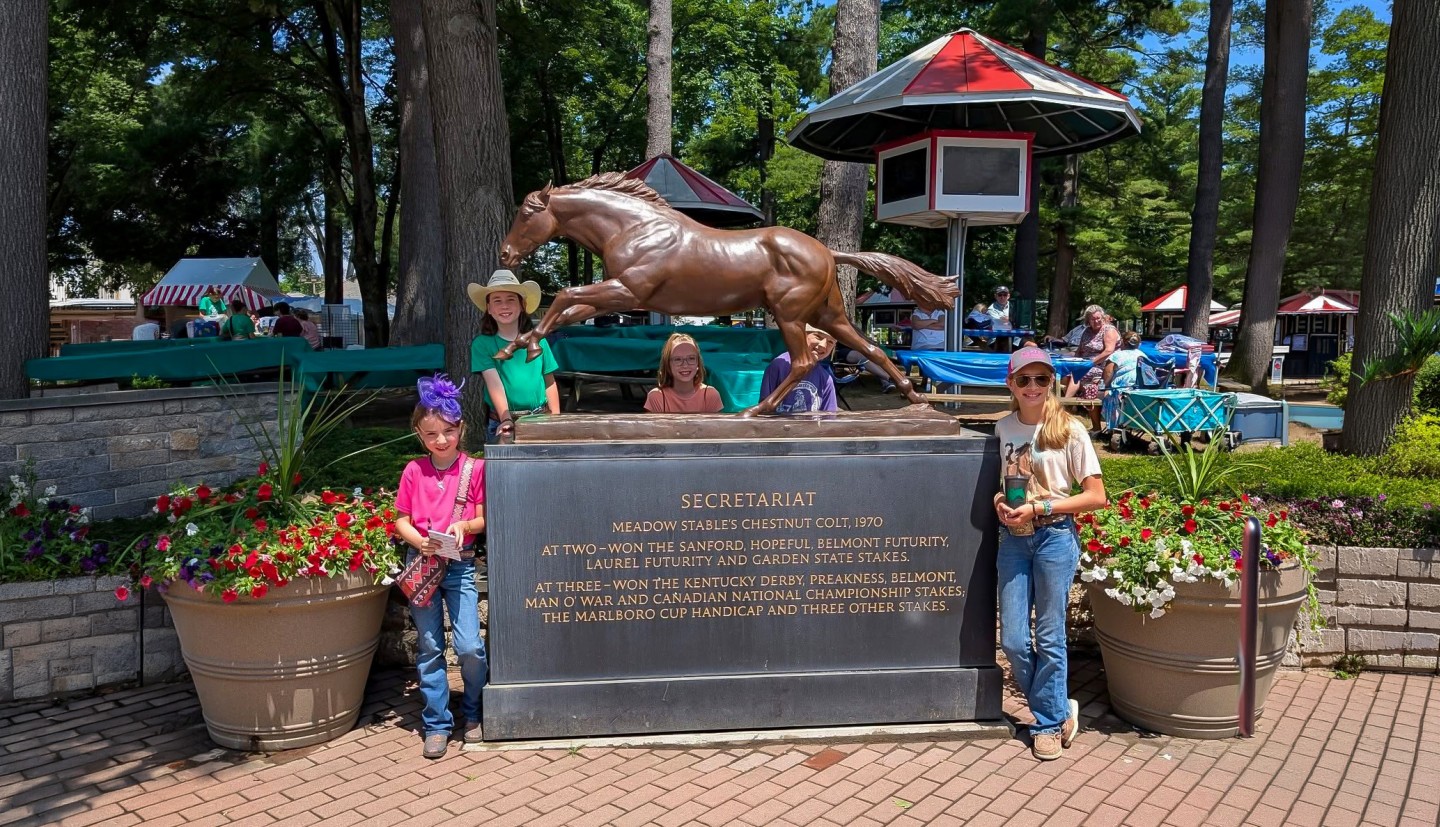 Youth stand next to a statue of Secretariat