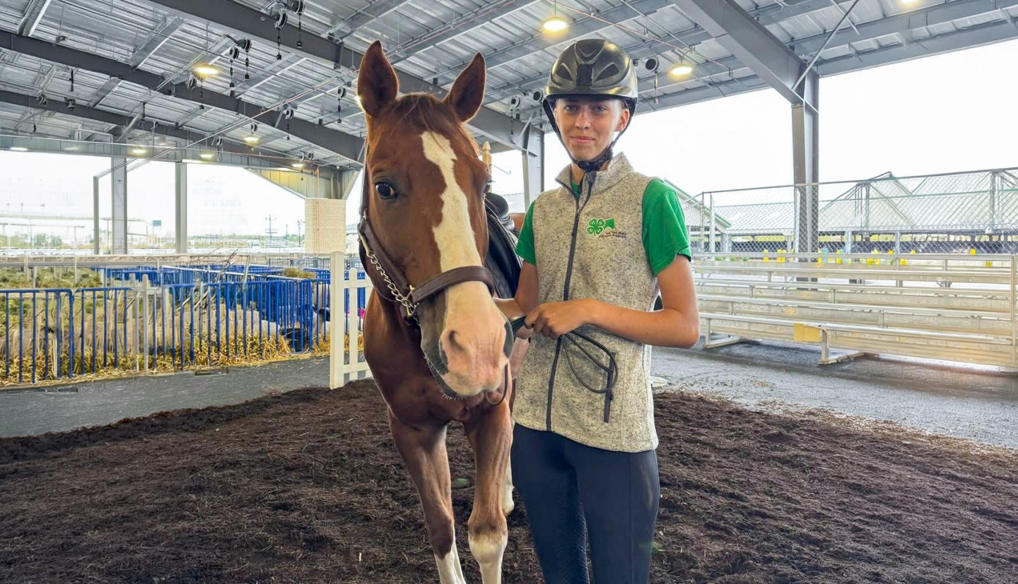 a girl stands beside a horse