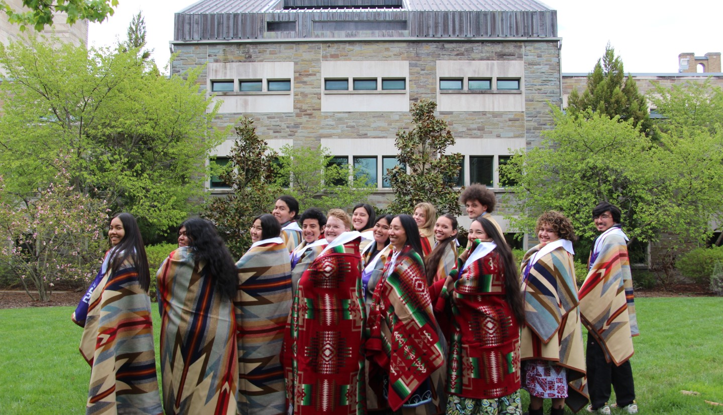 AIISP graduates stand in a courtyard wrapped in Pendleton blankets.