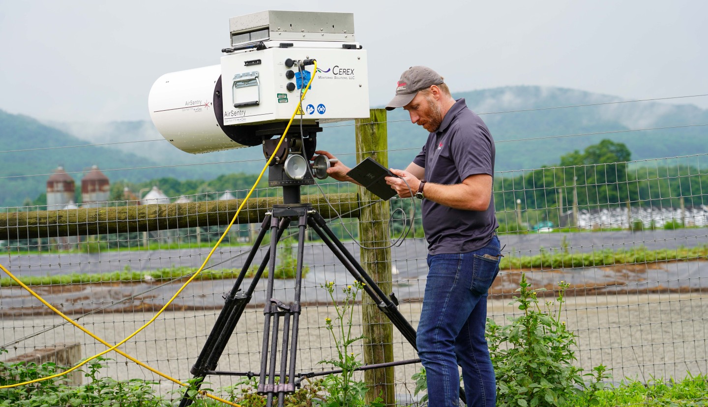 a man looks at a gas sensor set up by a manure pit