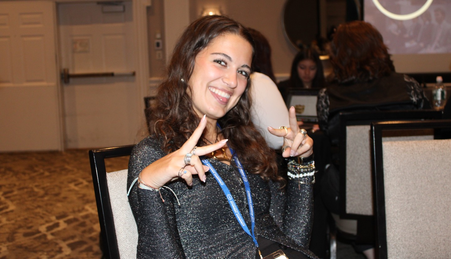 Girl in a chair making a peace sign with her fingers