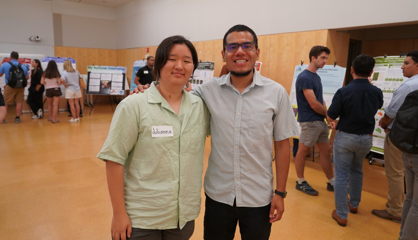A woman and a man stand next to each other in a large room, smiling.