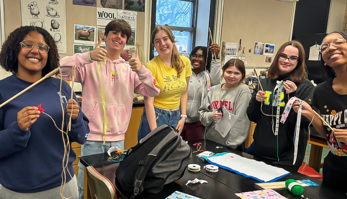 a group of people stand holding materials and finished cat toys