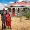 Farmers stand outside their house
