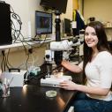 Breanne Kisselstein sits with a microscope