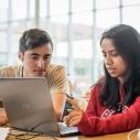 Two students collaborating at a laptop in Schurman Hall atrium