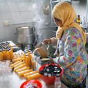 A woman standing in a kitchen pouring sauce into bottles