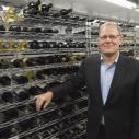 A man stands in front of shelves containing bottles of wine
