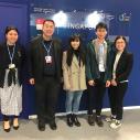 Four college students and one man stand in front of a sign for the delegation of Singapore