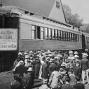 A group of people wait for a train with a special label in the 20th century