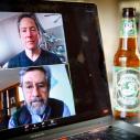 A computer laptop screen shows two men discussing beer.