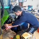 A male student working on a green tractor