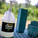 A large pump bottle of hand sanitizer on a table next to green cardboard blueberry boxes 