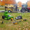 A tractor pulling a trailer with several lawn care tools 