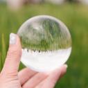 Spherical glass inverts image of people standing in a field