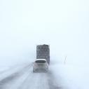 A car and a truck driving along a very snowy road